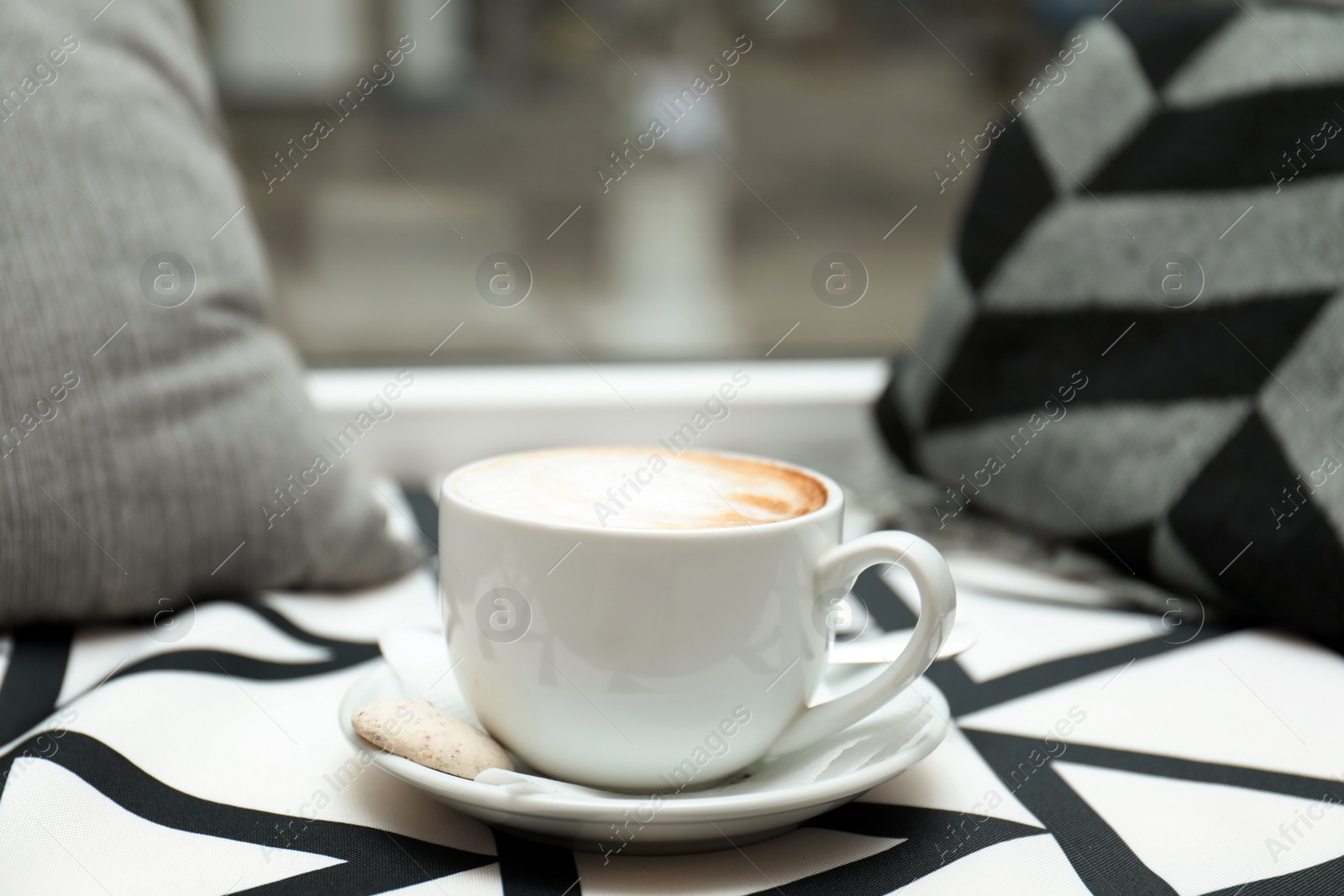 Photo of Cup of aromatic cacao on table against blurred background. Space for text