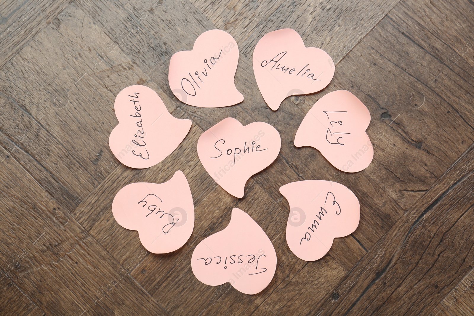 Photo of Paper stickers with different names on wooden background, flat lay. Choosing baby's name