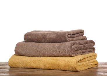 Photo of Soft colorful terry towels on wooden table against white background