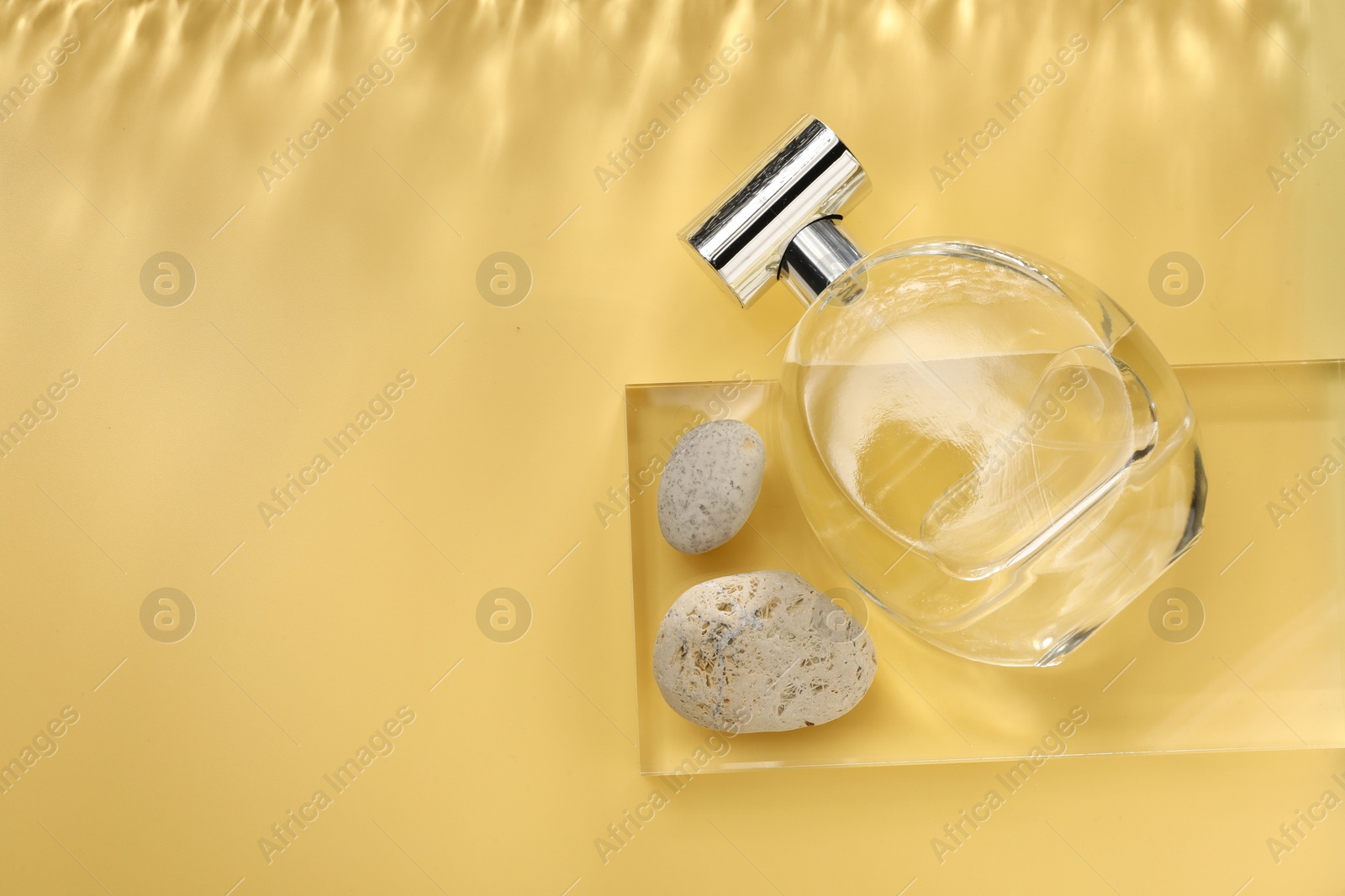 Photo of Stylish presentation of luxury perfume in bottle on golden background, flat lay. Space for text