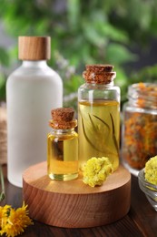 Photo of Bottles of essential oils and different herbs on wooden table