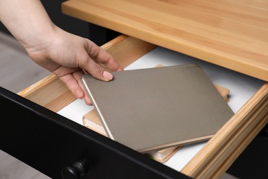 Photo of Woman putting notebook into desk drawer, closeup