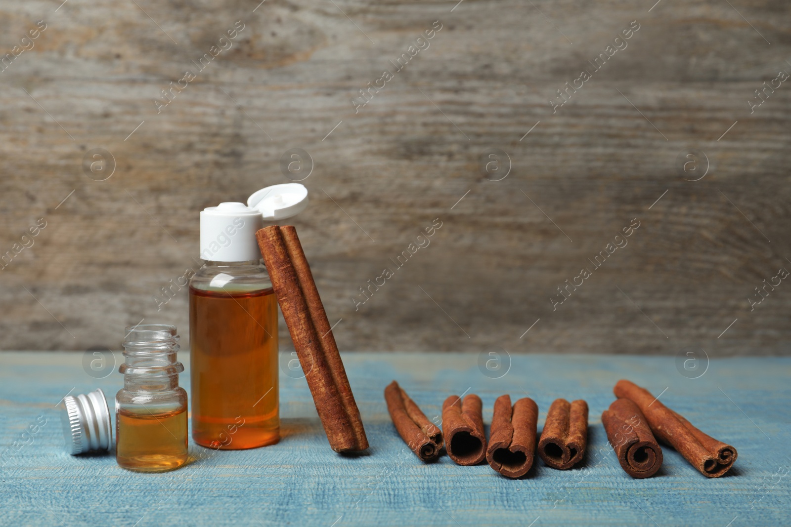 Photo of Bottles with cinnamon oil and sticks on wooden table