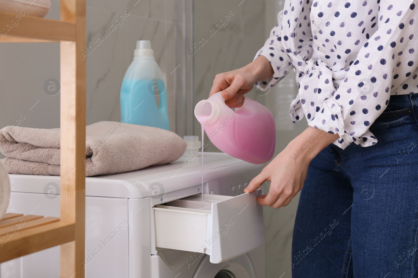 Photo of Woman pouring detergent into washing machine drawer in bathroom, closeup. Laundry day