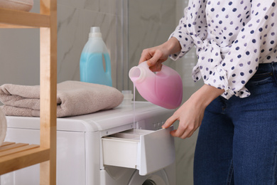 Photo of Woman pouring detergent into washing machine drawer in bathroom, closeup. Laundry day