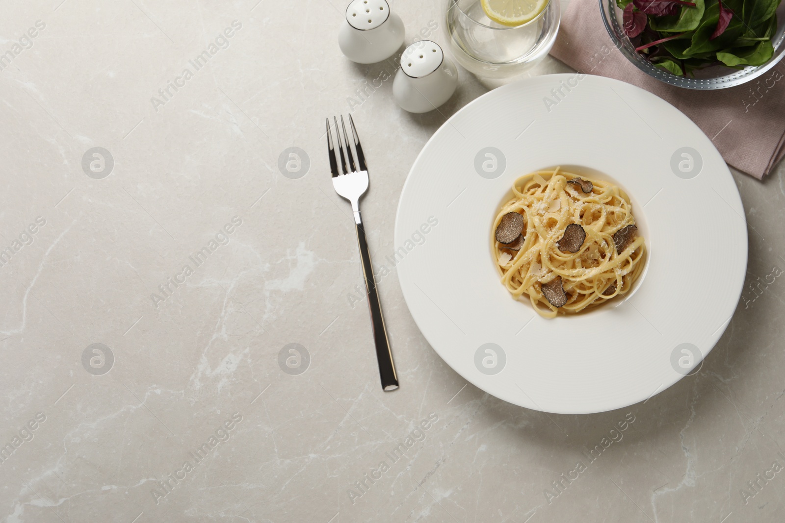 Photo of Delicious pasta with truffle slices and cheese served on light grey table, flat lay. Space for text