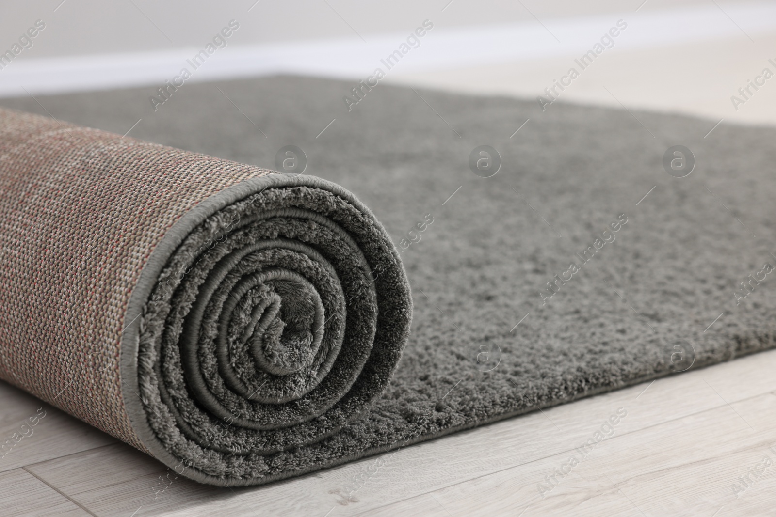 Photo of Rolled grey carpet on floor in room, closeup
