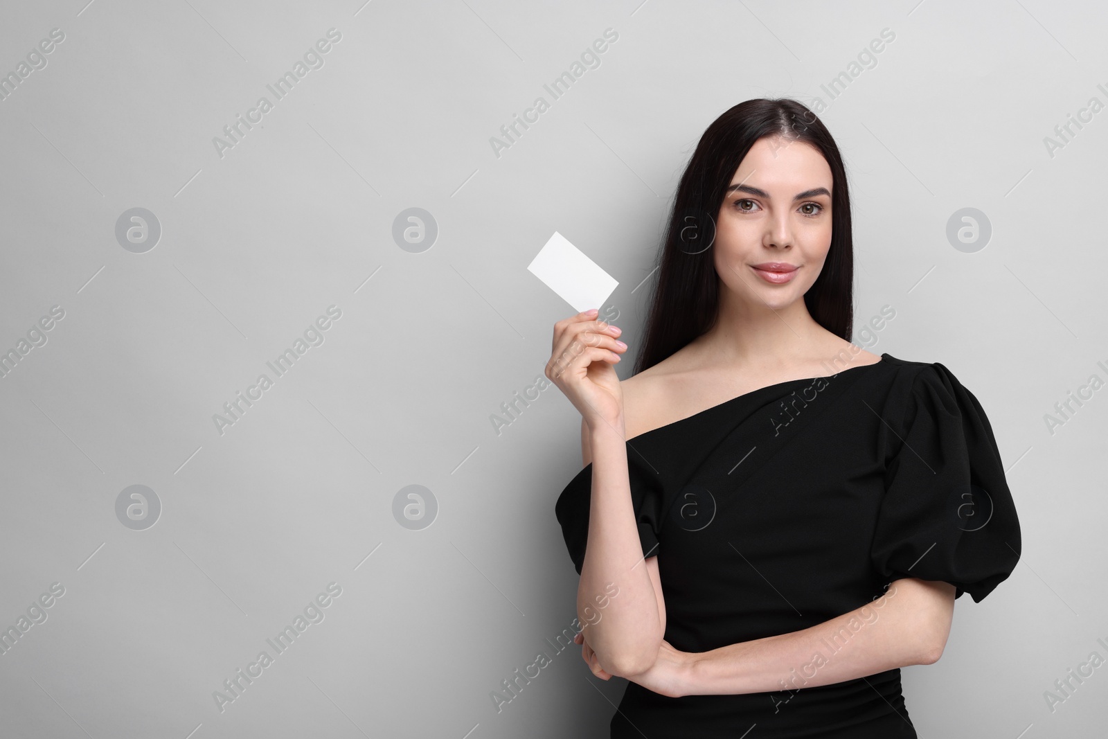 Photo of Woman holding blank business card on light grey background. Space for text