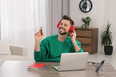 Man in headphones listening speaker at online translation course on laptop in room