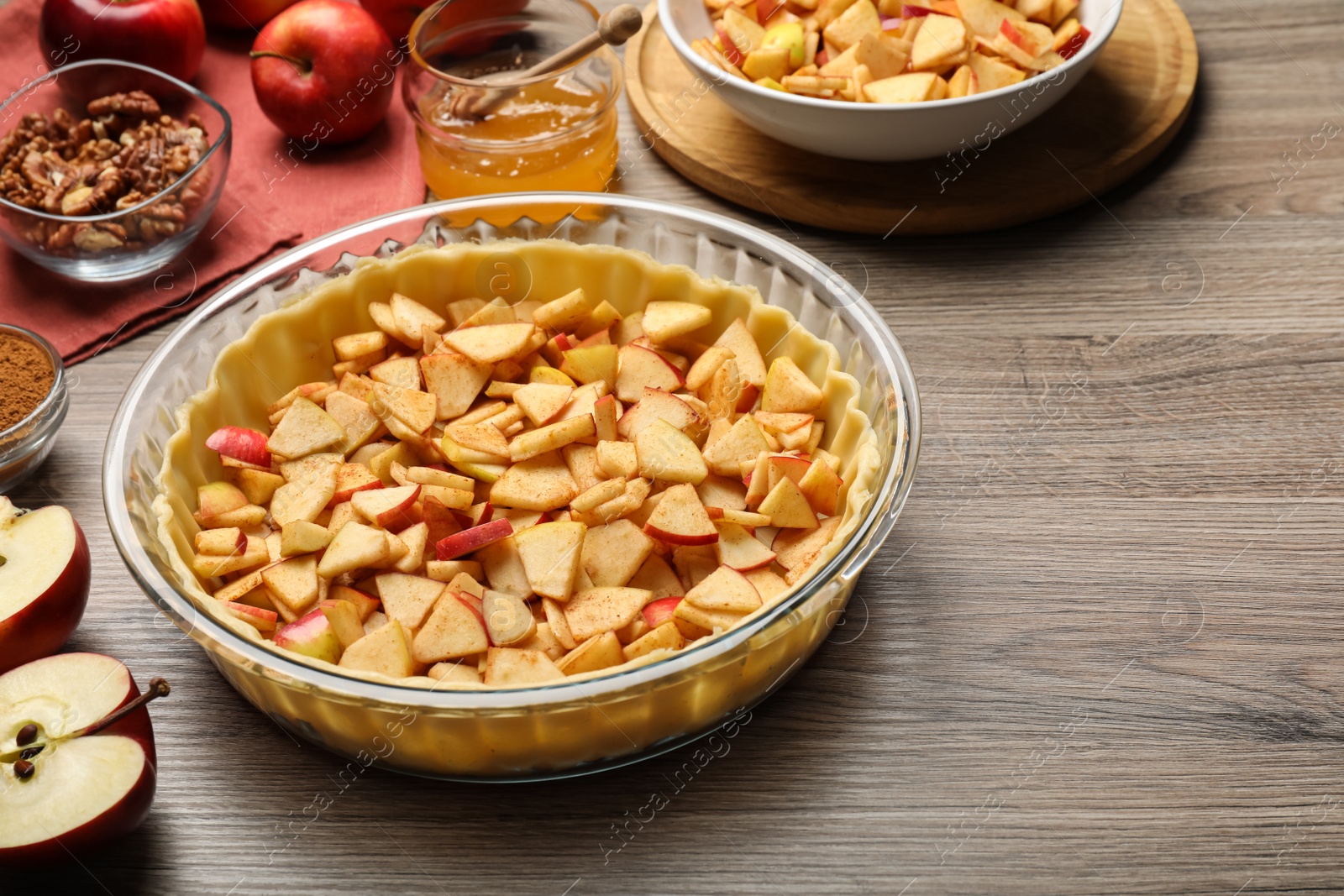 Photo of Raw dough and ingredients for apple pie on wooden table