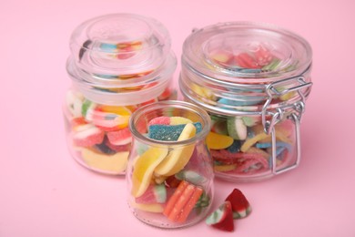 Photo of Tasty jelly candies in jars on pink background, closeup