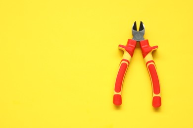 Photo of Diagonal pliers on yellow background, top view. Space for text