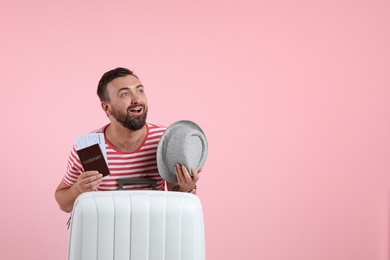 Man with suitcase, passport and hat on color background. Space for text