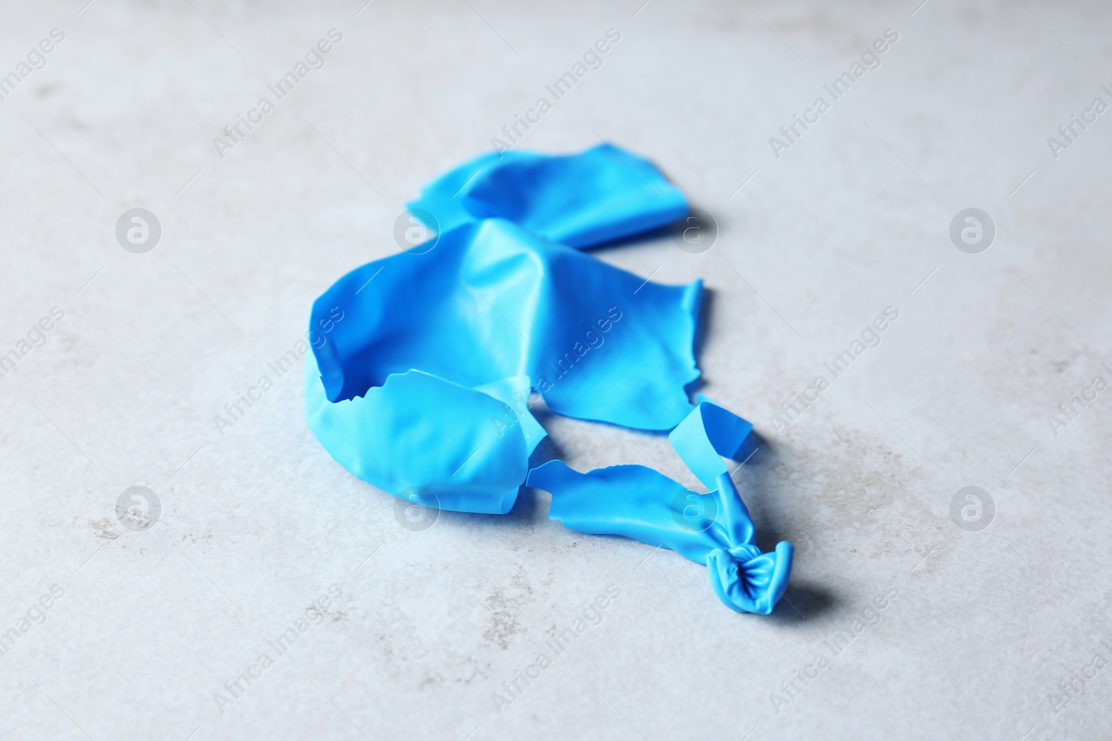 Photo of Popped blue latex balloon on grey background