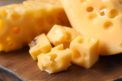 Photo of Pieces of delicious cheese on wooden board, closeup