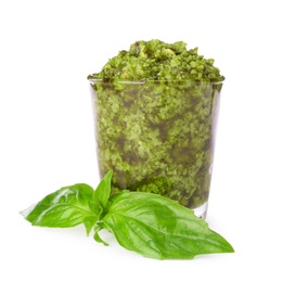Photo of Glass of tasty pesto sauce and basil leaves isolated on white
