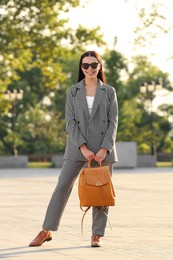 Beautiful young woman with stylish backpack on city street