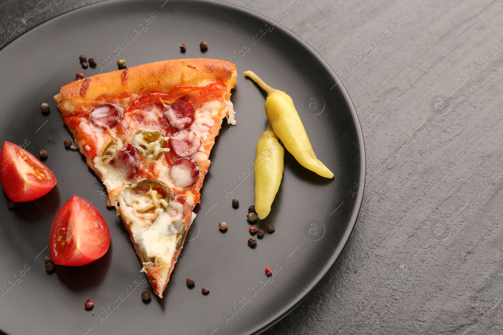 Photo of Plate with delicious pizza Diablo, pepper, tomato and peppercorns on dark textured table, closeup. Space for text