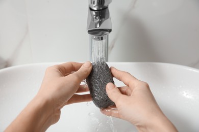 Photo of Woman pouring water onto pumice stone in bathroom, closeup