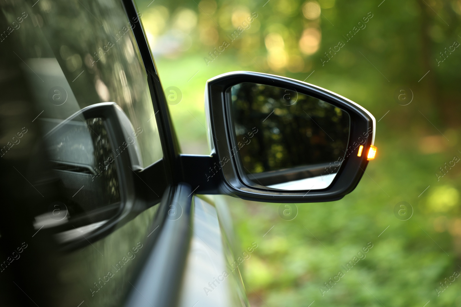 Photo of Side view mirror of modern car on blurred background, closeup