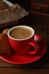 Photo of Delicious heart shaped cookies and cup of coffee on wooden table, closeup