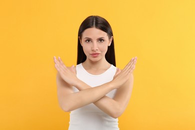 Photo of Woman with crossed hands on orange background. Stop gesture