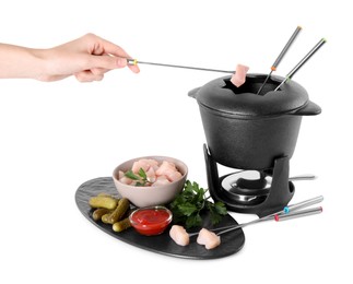 Photo of Woman dipping piece of raw meat into oil in fondue pot on white background
