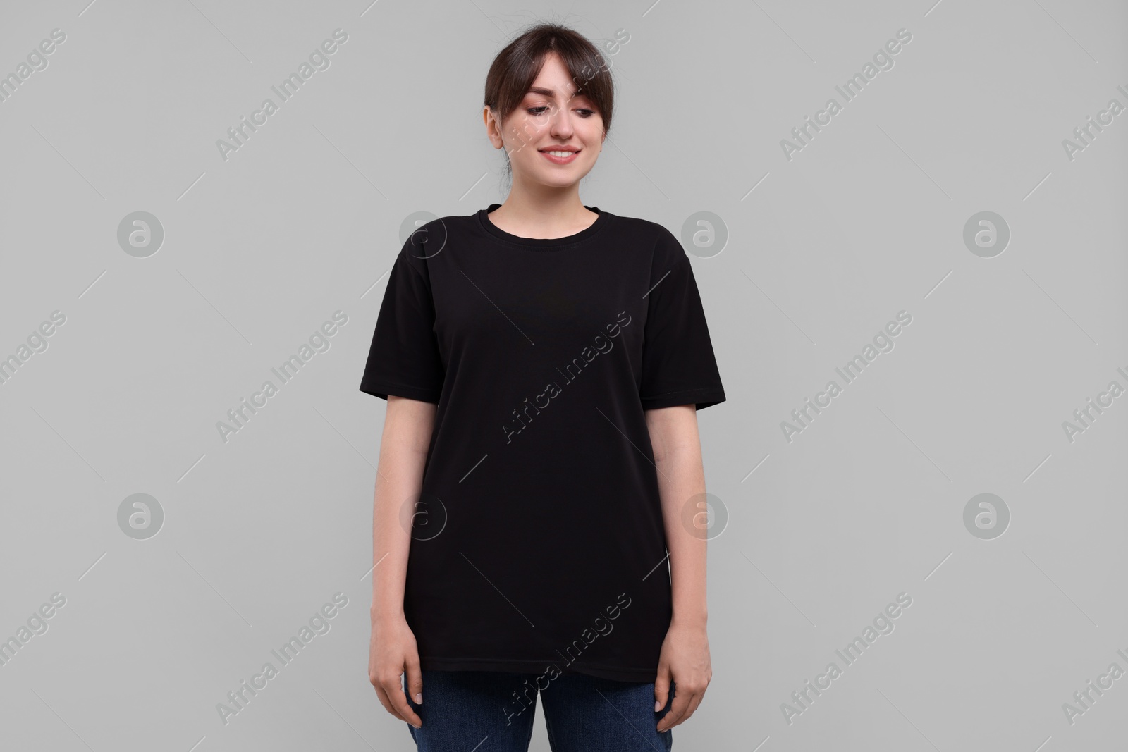 Photo of Smiling woman in stylish black t-shirt on light grey background