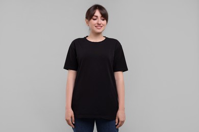 Smiling woman in stylish black t-shirt on light grey background