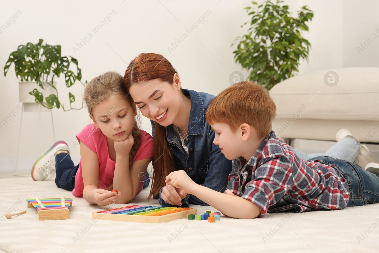 Photo of Happy mother and children playing with different math game kits on floor in room. Study mathematics with pleasure