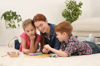 Photo of Happy mother and children playing with different math game kits on floor in room. Study mathematics with pleasure