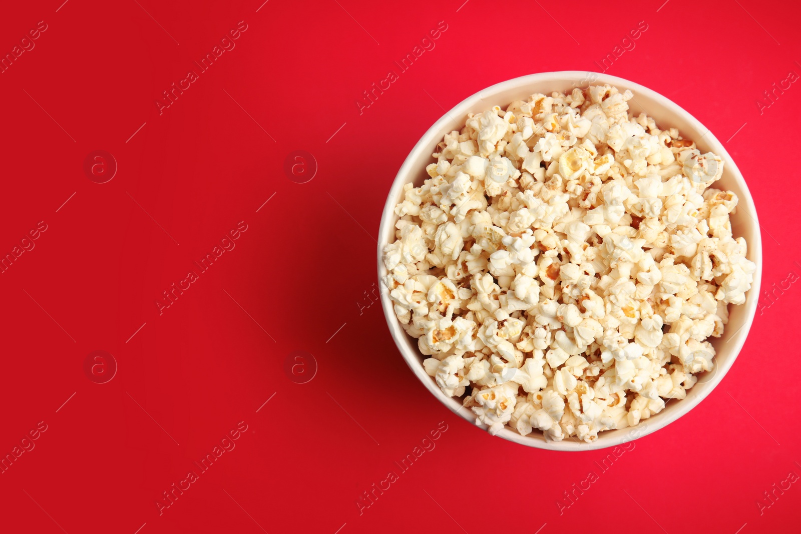 Photo of Tasty pop corn on red background, top view. Space for text