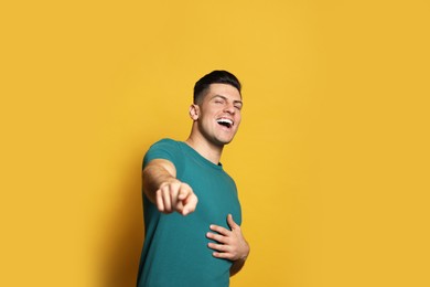 Photo of Handsome man laughing on yellow background. Funny joke