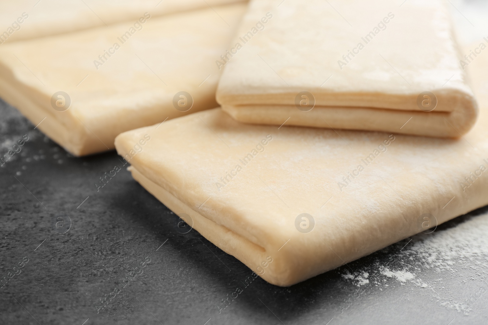 Photo of Raw wheat dough and flour on grey table