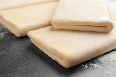 Raw wheat dough and flour on grey table