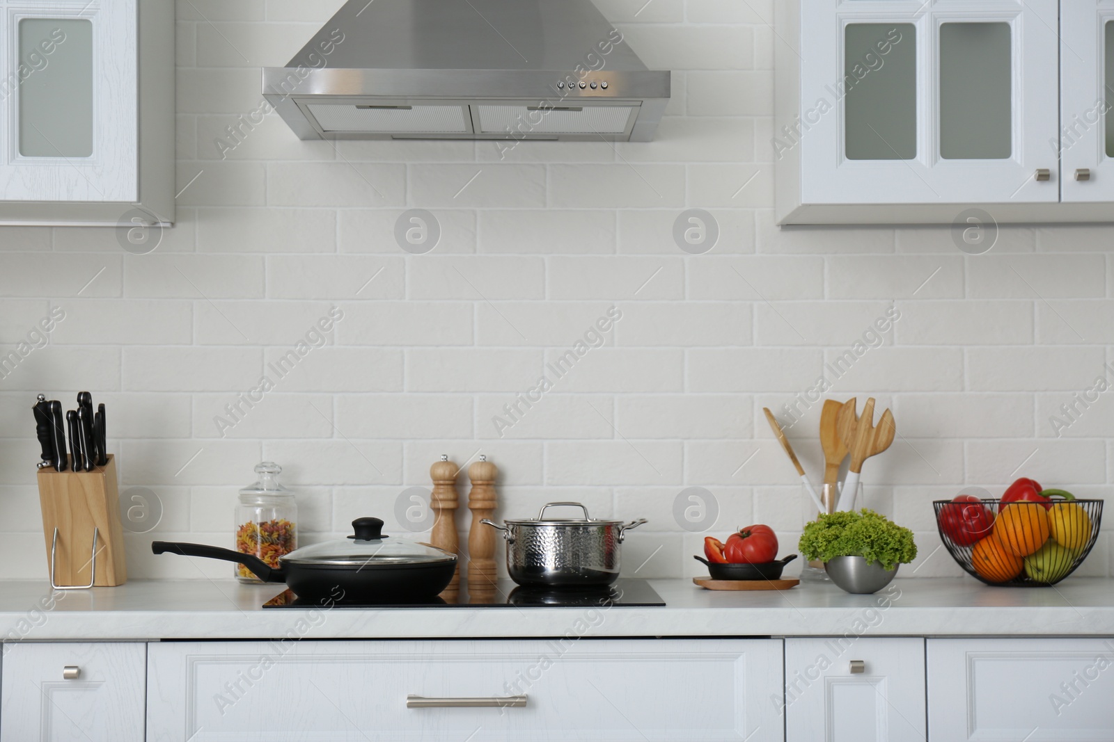 Photo of Counter with set of dishware, utensils and products in stylish kitchen interior