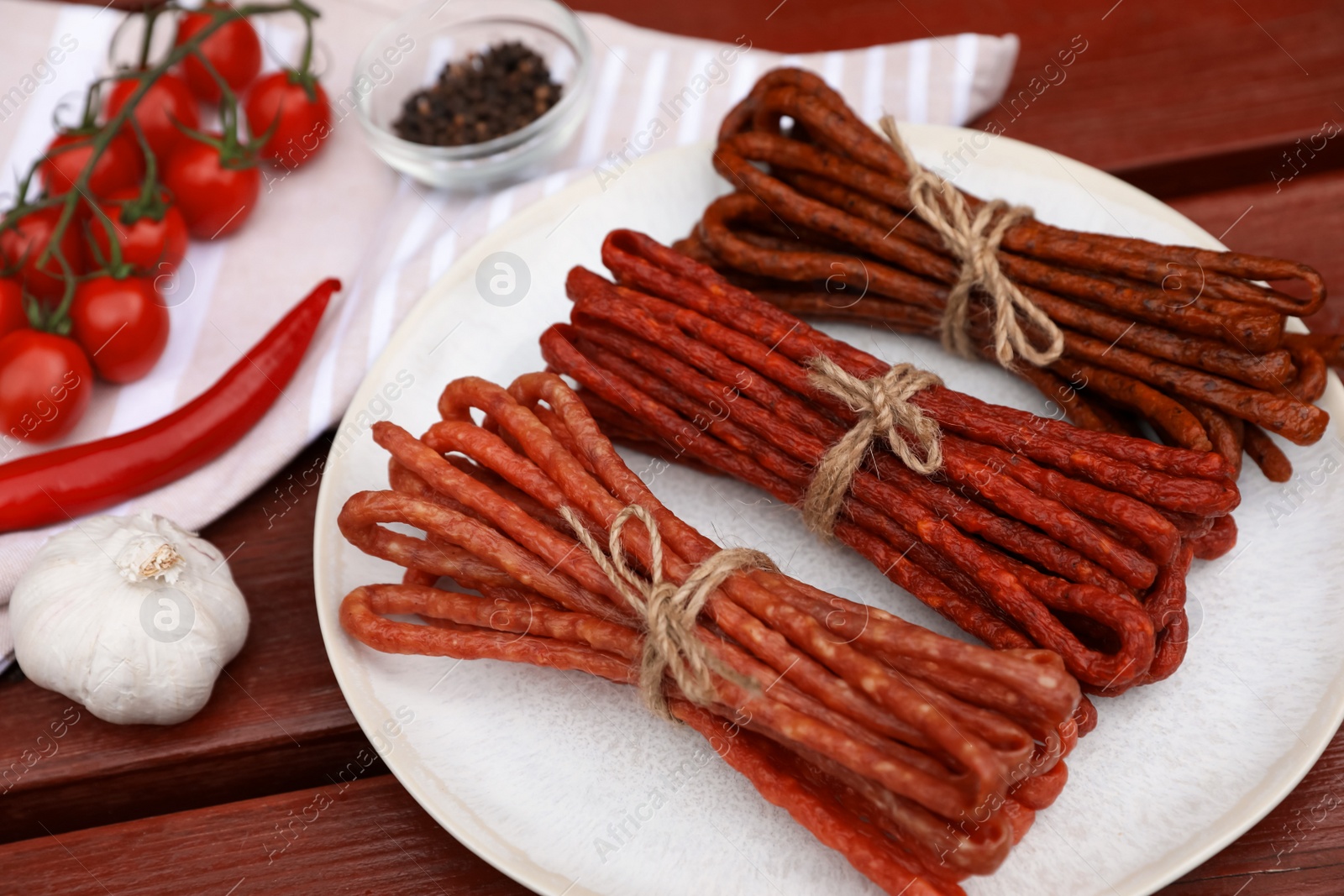 Photo of Bundles of delicious kabanosy and different products on wooden table