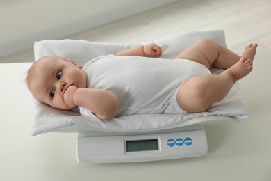 Photo of Cute little baby lying on scales in clinic