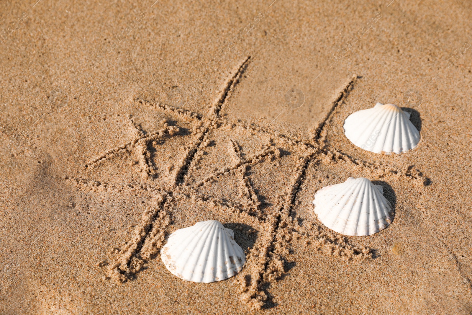 Photo of Playing Tic tac toe game with shells on sand