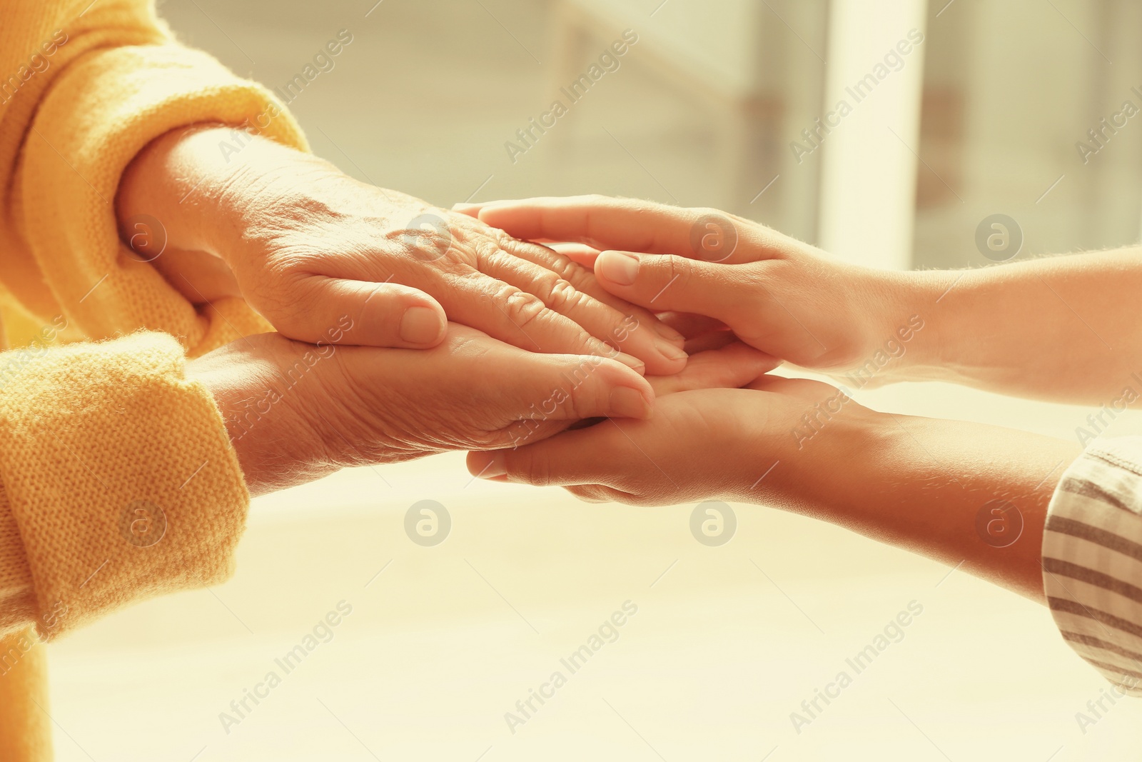 Image of Helping hands on blurred background, closeup. Elderly care concept