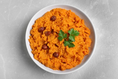 Photo of Bowl of tasty sweet potato puree on grey marble table, top view