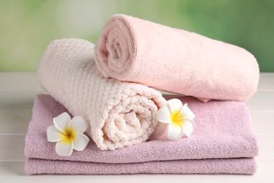Photo of Closeup viewsoft folded towels and plumeria flowers on white wooden table