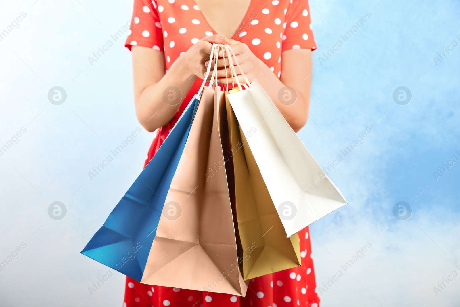 Photo of Woman holding paper shopping bags on color background