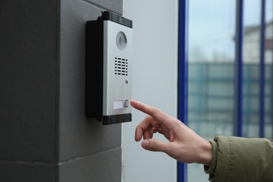 Photo of Man ringing intercom with camera near building entrance, closeup