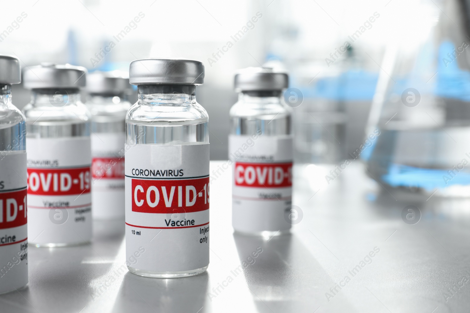 Photo of Glass vials with COVID-19 vaccine on light table. Space for text