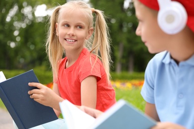 Photo of Cute boy in headphones and girl reading books in green park