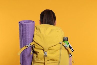 Photo of Woman with backpack on orange background, back view. Active tourism
