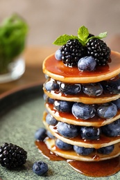 Tasty pancakes with berries and syrup on plate