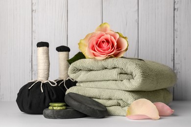 Photo of Composition with different spa products and rose on white table against wooden background