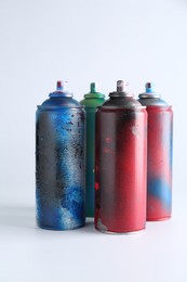 Many spray paint cans on white background
